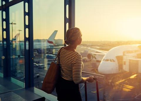 Women looking out of airport window representing mistakes your business should avoid when booking travel.