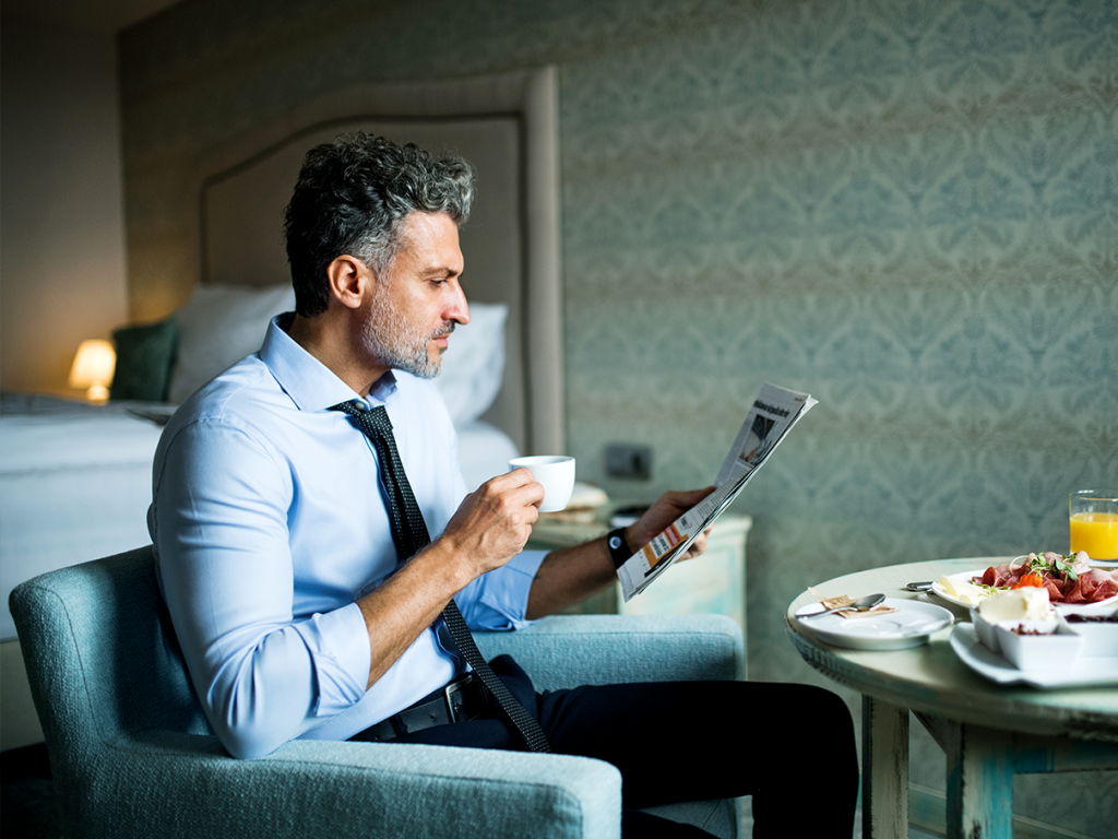 Business man drinking coffee while reading a newspaper