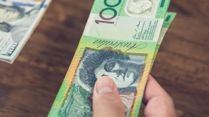 Hand holding Australian dollars highlighting the importance of paying in AUD overseas