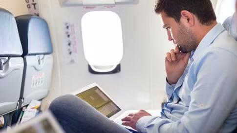 Man working from an airline seat representing the perks of getting the best seats on the plane