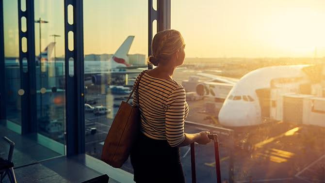 Women looking out of airport window representing mistakes your business should avoid when booking travel.